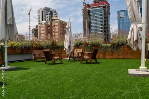 Urban rooftop garden with wooden furniture, artificial grass, and cityscape backdrop in Ramat Gan, Israel © Olga Mazo