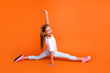 Full length profile photo of cheerful sportive girl rejoice good mood split legs isolated on orange color background
