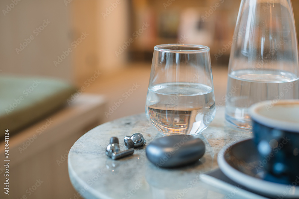 Glass of water, headphones, coffee cup on marble table.