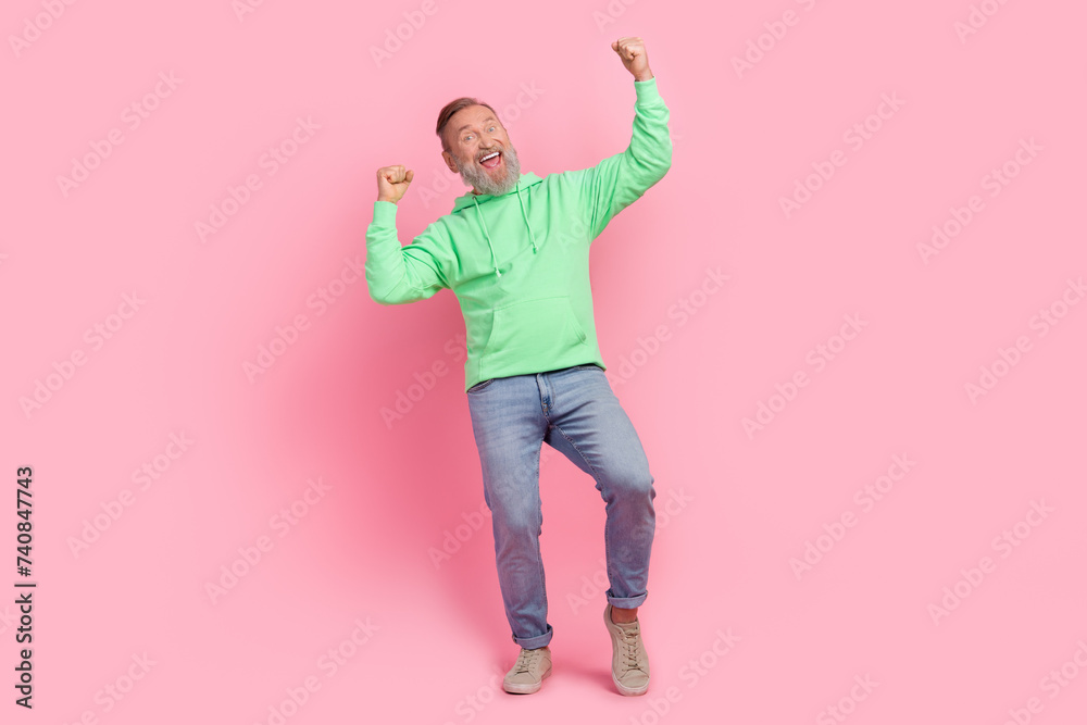 Full size photo of cool pensioner man raise fists celebrate lottery champion wear trendy green clothes isolated on pink color background Full size photo of cool pensioner man raise fists celebrate lottery champion wear trendy green clothes isolated on pink color background