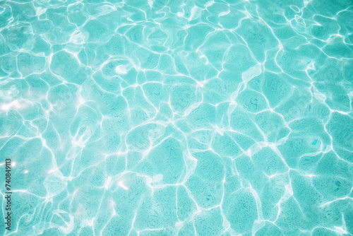 Background, blue water waves in the pool with sun reflection. Top view, selective focus