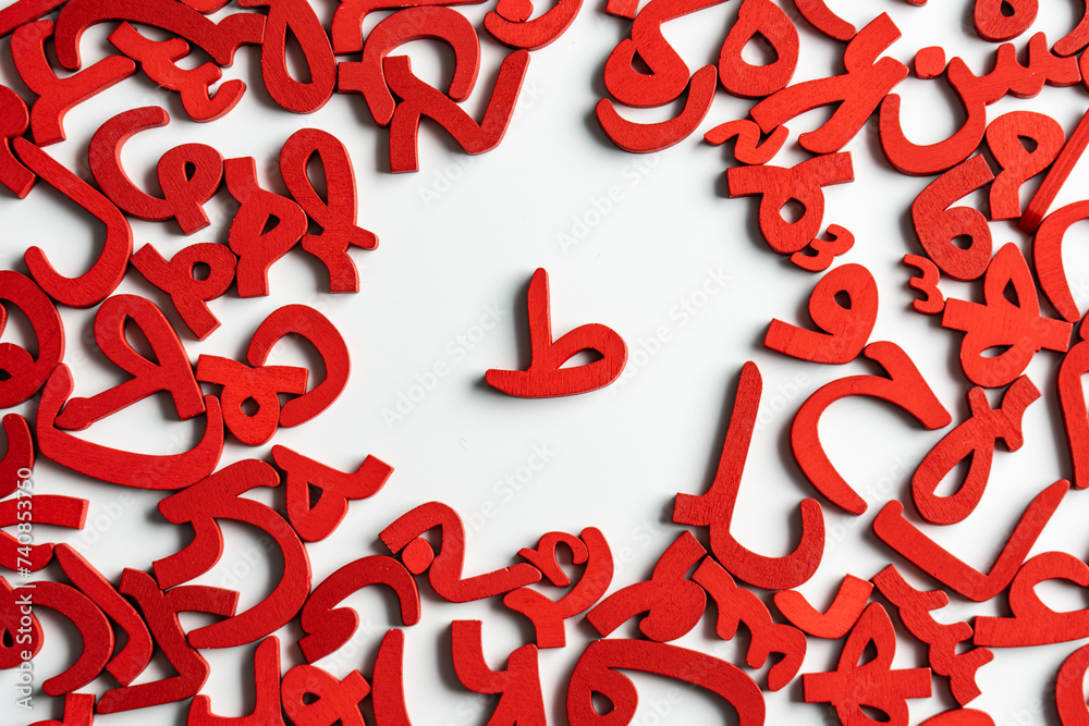 Topview picture of a group of Arabic letters made of wood, with the letter (TA) in the middle, colored red on a white background. Topview picture of a group of Arabic letters made of wood, with the letter (TA) in the middle, colored red on a white background.