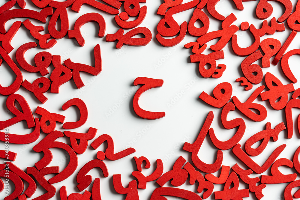 Topview picture of a group of Arabic letters made of wood, with the letter (HA) in the middle, colored red on a white background. Topview picture of a group of Arabic letters made of wood, with the letter (HA) in the middle, colored red on a white background.