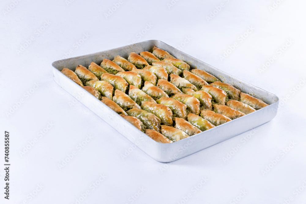 Top view of shaabiyat with pistachio baklava on tray isolated on white background. Traditional Turkish cuisine dessert with sherbet. Top view of shaabiyat with pistachio baklava on tray isolated on white background. Traditional Turkish cuisine dessert with sherbet.