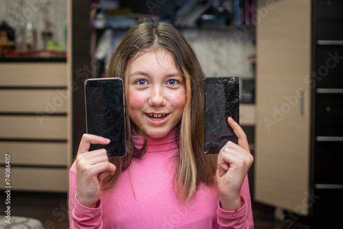 A cheerful girl broke two phones. A child broke the screens of two smartphones
