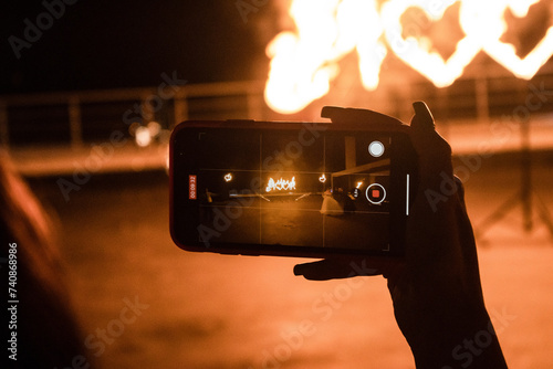 Fire show. The girl takes a video on her phone. Burning hearts.