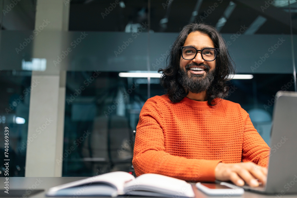 Millennial eastern man working at computer in modern office Millennial eastern man working at computer in modern office