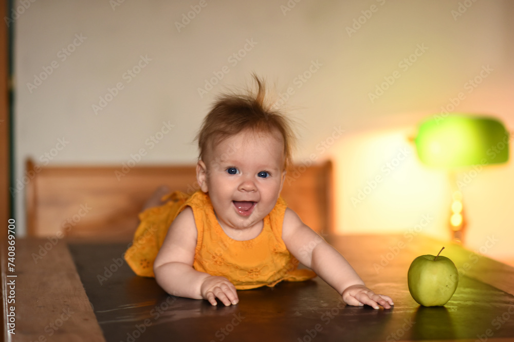 Small child with a green apple. The baby is lying on his stomach. A 4 month old baby lies on his stomach and holds his head. Small child with a green apple. The baby is lying on his stomach. A 4 month old baby lies on his stomach and holds his head.