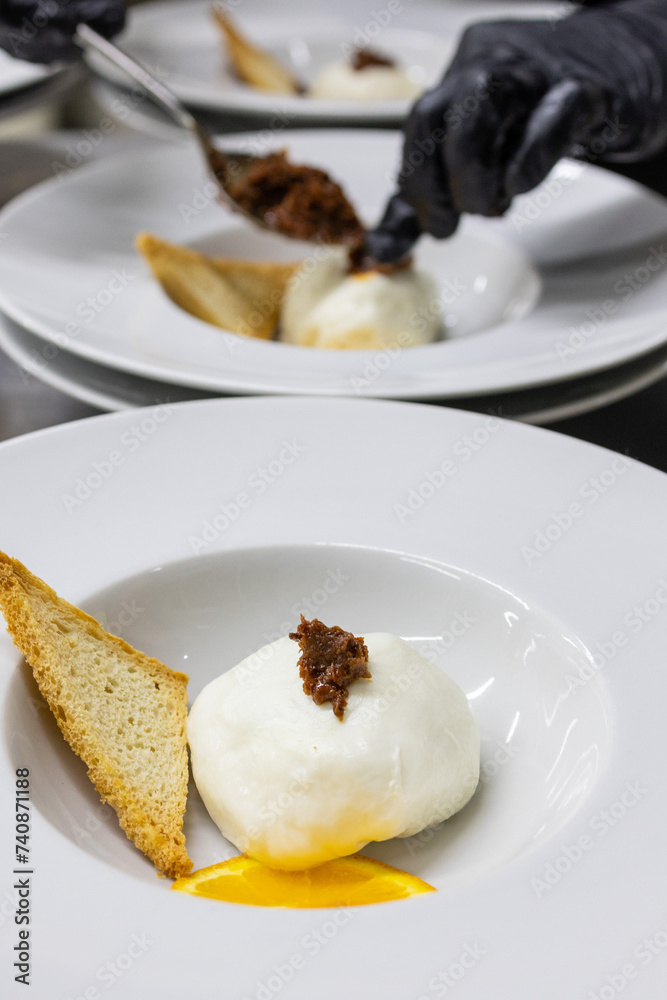 Chef di un ristorante da cerimonia mentre guarnisce i piatti in uscita del menù Chef di un ristorante da cerimonia mentre guarnisce i piatti in uscita del menù