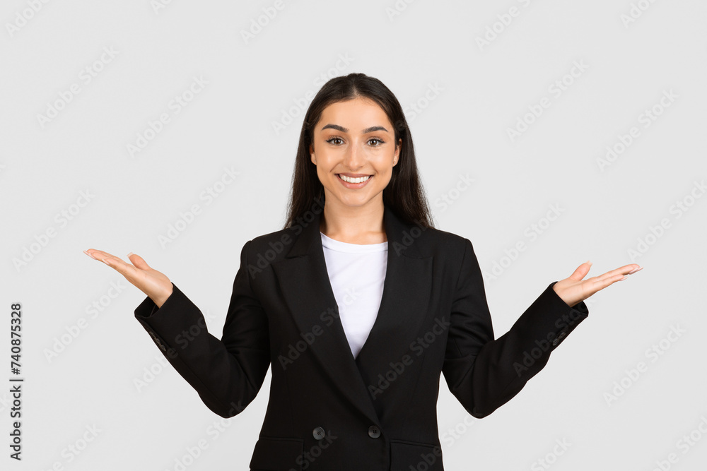 Confident woman in black suit with hands open in welcoming gesture Confident woman in black suit with hands open in welcoming gesture