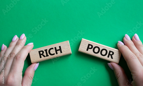 Rich vs Poor symbol. Concept word Rich vs Poor on wooden blocks. Businessman hand. Beautiful green background. Business and Rich vs Poor concept. Copy space
