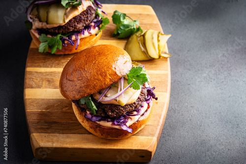 Beef burgers with pickles and red onion on cutting board, copy space