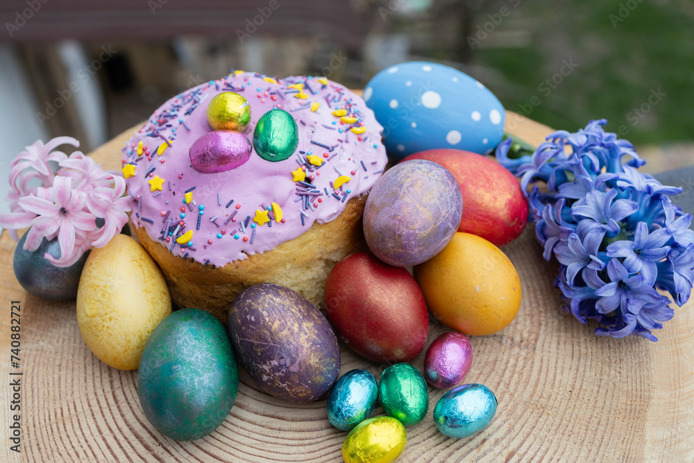 Fototapeta premium multi-colored Easter eggs, homemade Easter cake decorated with chocolate eggs in foil and a large hyacinth flower. Easter concept. Christ is risen. Orthodox holiday