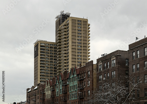 tall modern high rise low income apartment building towering above old pre-war historic apartment buildings in brooklyn new york city (projects, tower, towers) neighborhood real estate