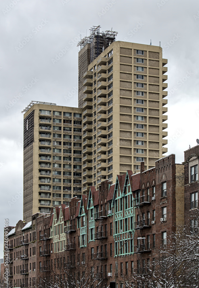 tall modern high rise low income apartment building towering above old pre-war historic apartment buildings in brooklyn new york city (projects, tower, towers) neighborhood real estate