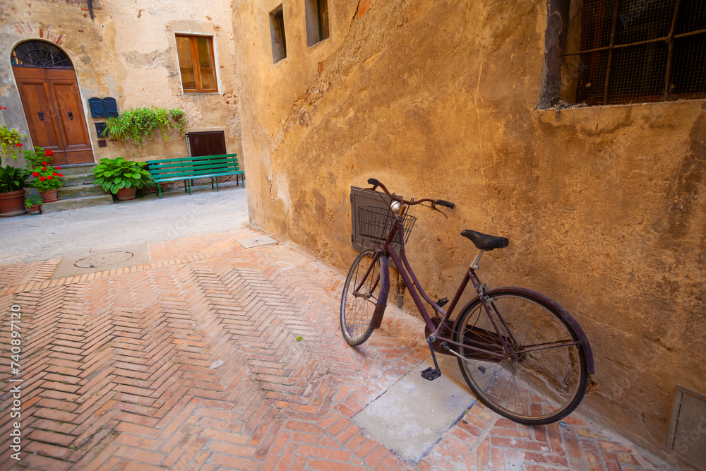 Serene corner of Pienza: vintage bike, old house, and tranquil atmosphere.