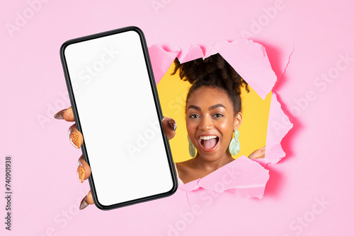 Glad excited young african american woman with open mouth showing mobile phone with blank screen © Prostock-studio