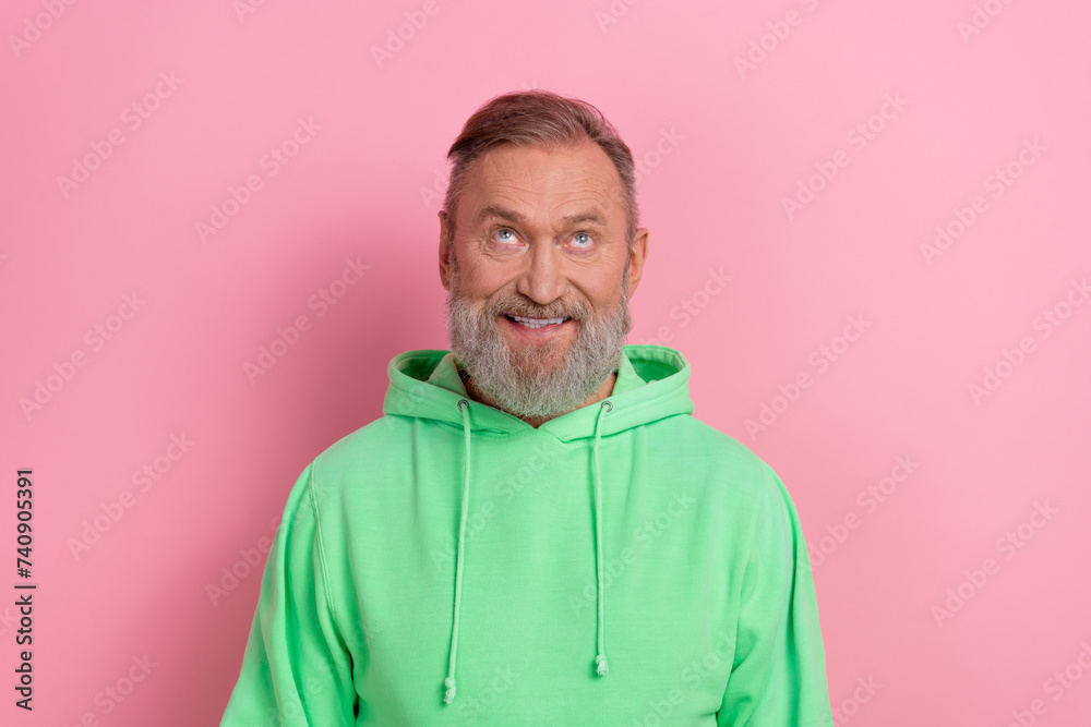 Obraz premium Photo of cheerful positive guy dressed green hoodie looking up empty space isolated pink color background