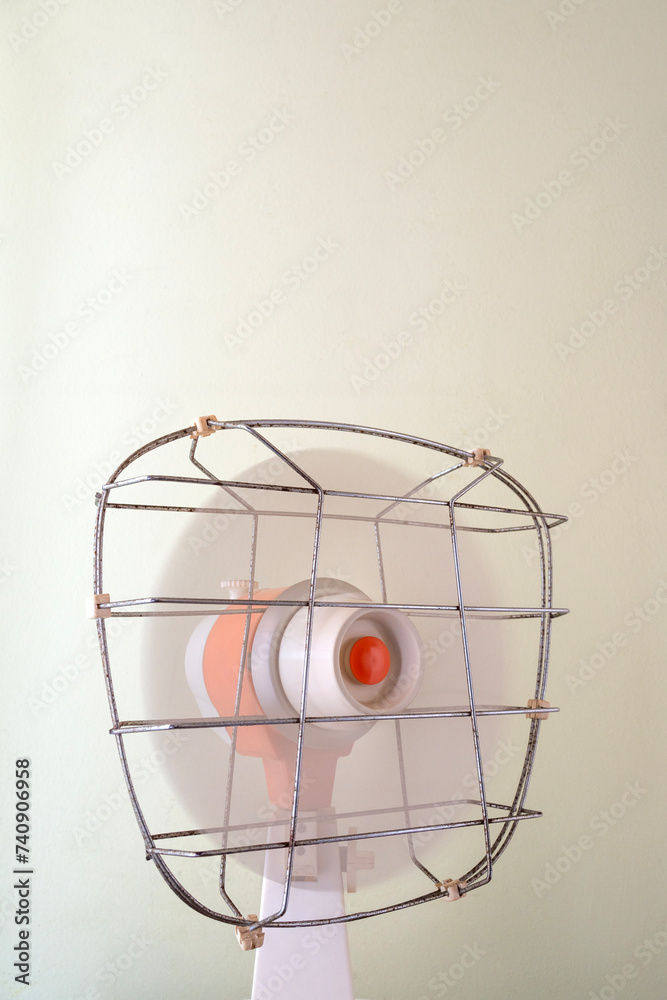 custom made wallpaper toronto digitalfan oscillating from right to left on a plain background, old, small, retro design, cream and orange with metal grille. Gives cooling air in the sweltering summer heat.