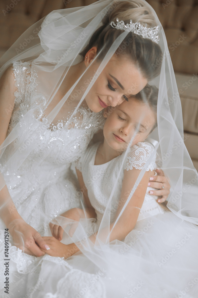 Portrait of the bride with her little sister in the room. Tender and sweet photo of a beautiful bride with her little sister. Portrait of the bride with her little sister in the room. Tender and sweet photo of a beautiful bride with her little sister.