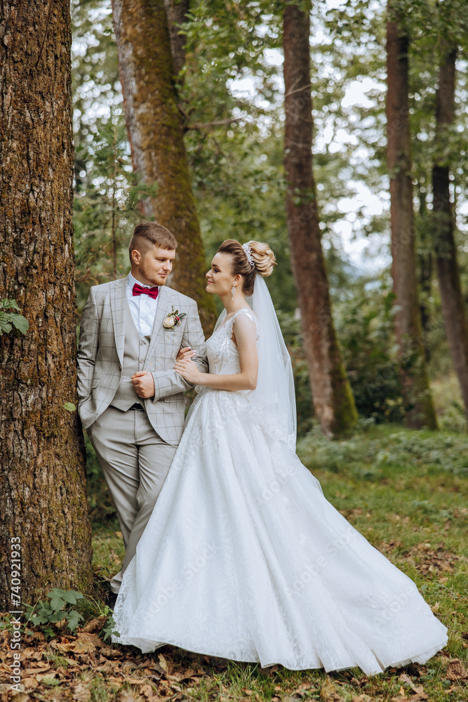 lovely and stylish newlyweds are hugging and smiling against the background of autumn nature in a beautiful garden. An incredibly beautiful young bride leaned against the shoulder of her beloved groom