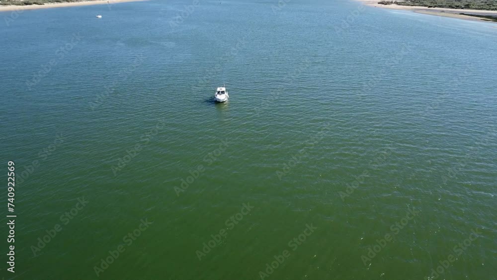 Aerial drone view of a motor boat moored in the Piedras river and fishing, Between the El Portil beach village and La Flecha sand bank