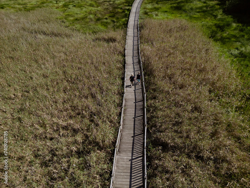 A visitor walks on the Catoira wooden river walk. Wooden walkway over the wetland next to the Ulla River in Catoira. photo