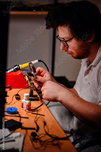 Focused Technician Soldering Electronics at a Cluttered Workstation
