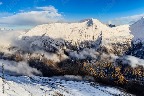 Bird's eye view from drone of snow mountain ridge and peak with cloud at sunset time at Dafeng base camp on the Siguniang Shan mountain in Changping Gou National Parks ,Rilong,Chengdu, China