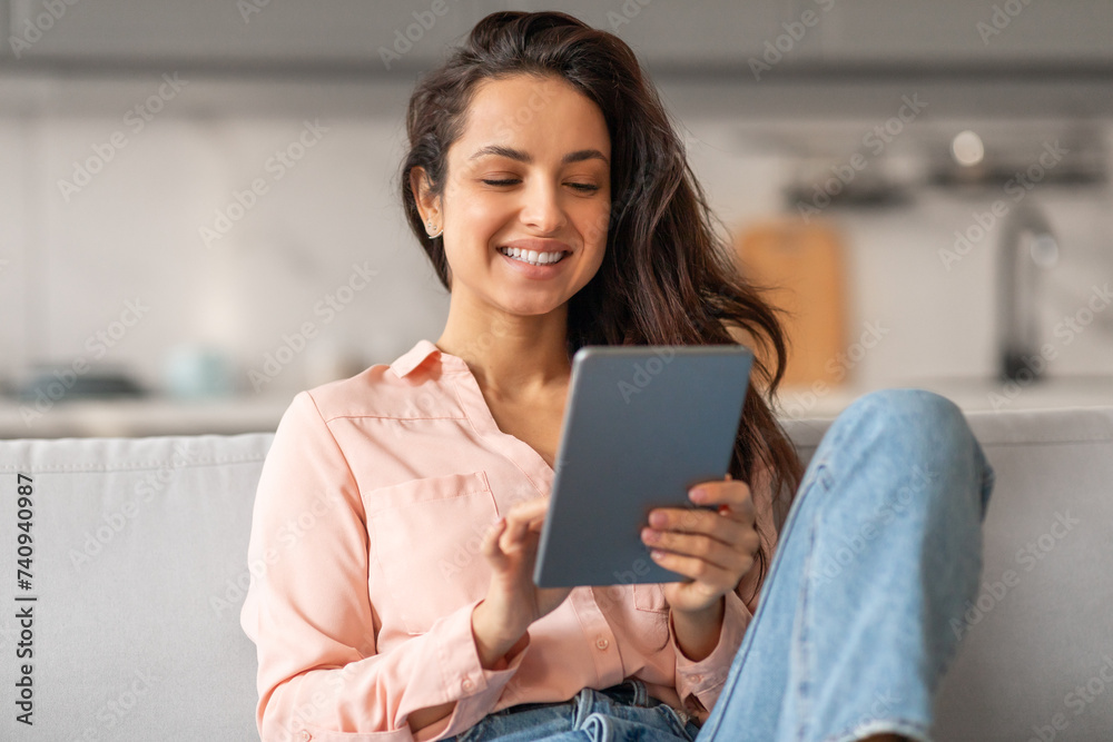 Happy woman using tablet on sofa at home