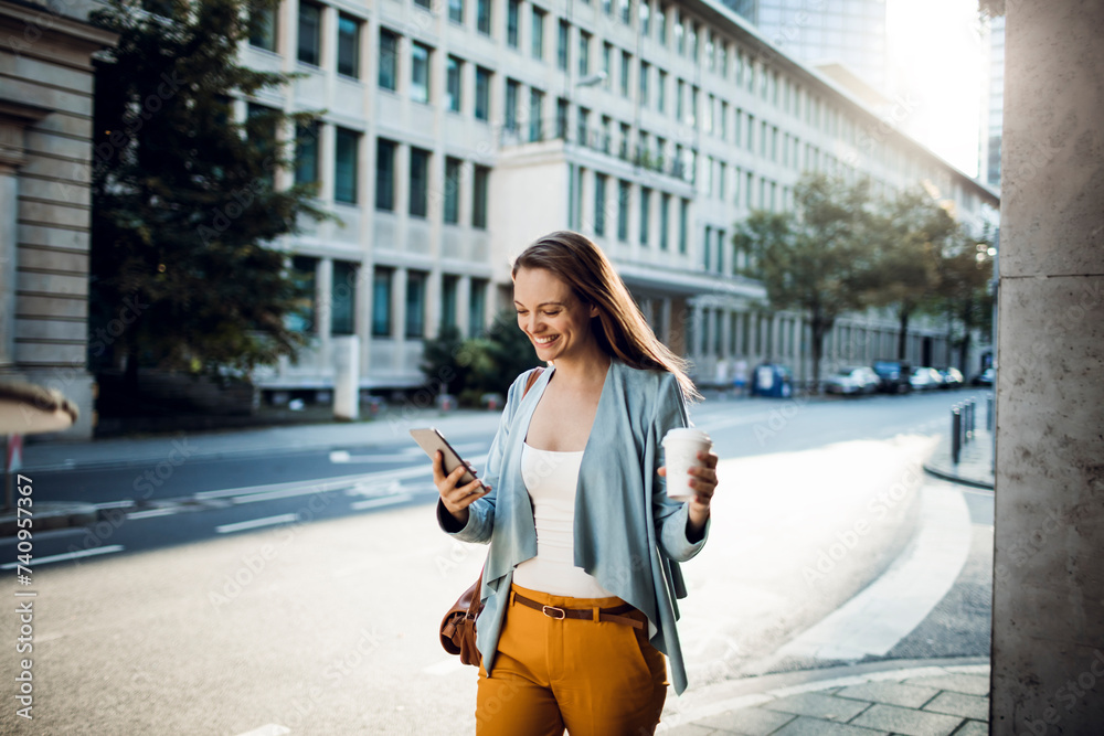 Fototapeta premium Young adult woman using her smart phone while commuting in the city