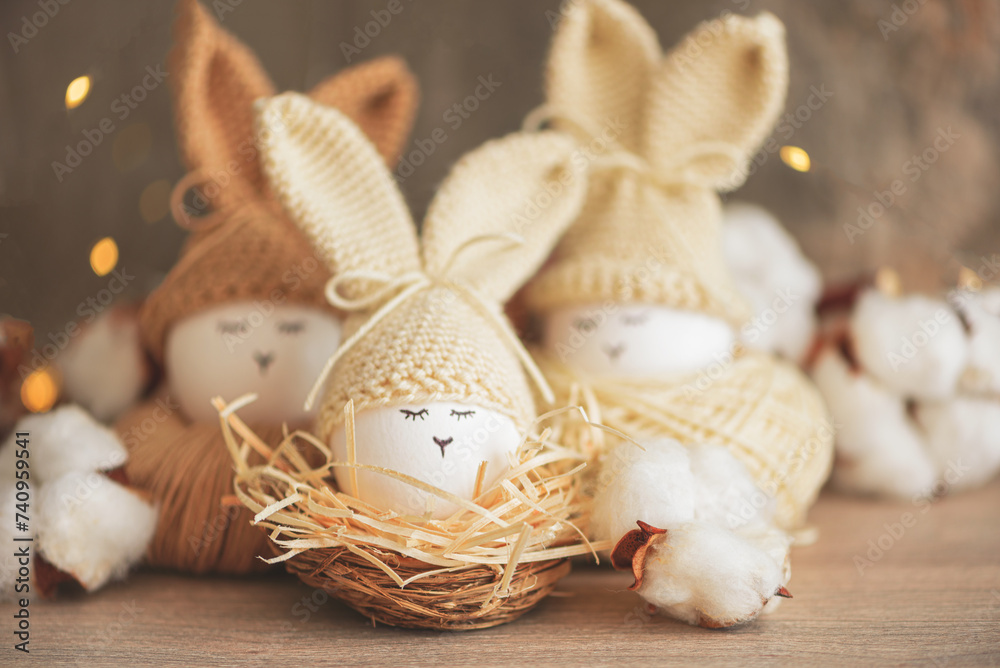 Easter eggs in crochet knitted hats with rabbit ears in nest. Easter celebration concept Easter eggs in crochet knitted hats with rabbit ears in nest. Easter celebration concept
