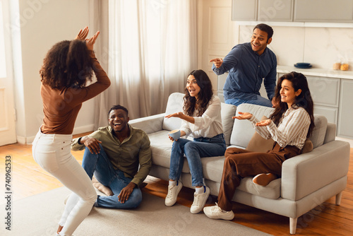 Diverse group of friends engages in game of charades indoors photo