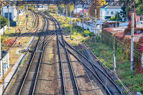 Branched railway tracks with automatic switches against the backdrop of urban warehouses and utility buildings. © Sergii