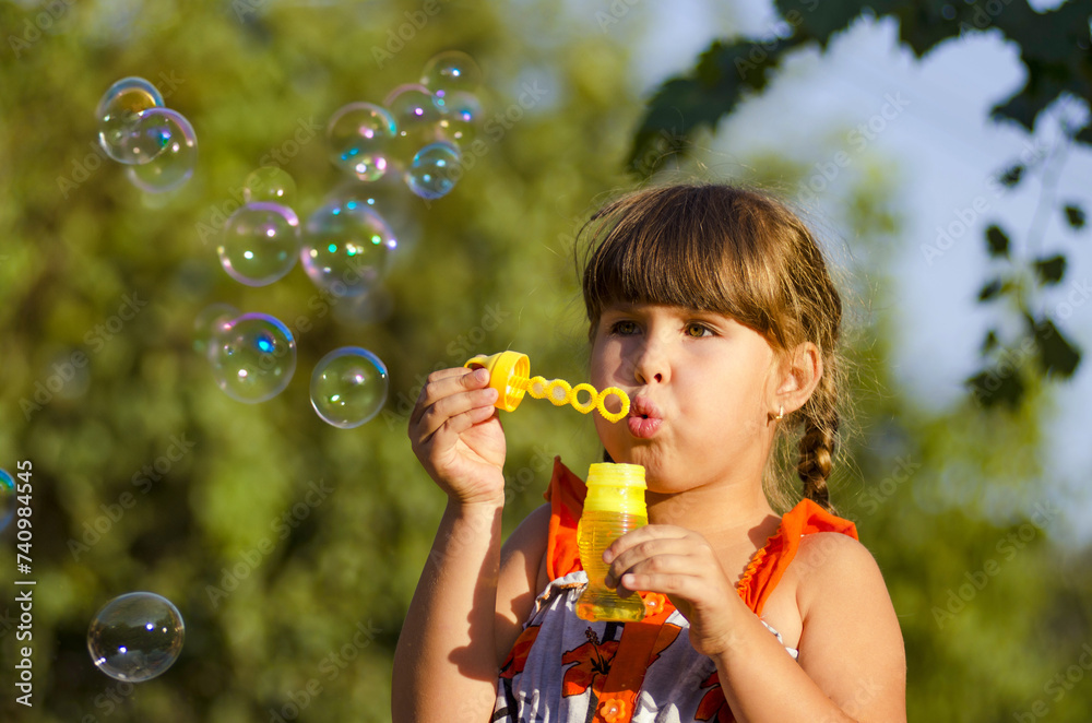 little girl playing with soap bubbles against the backdrop of a green park