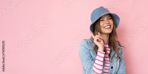 Beautiful girl in a denim hat and jacket on a pink background.