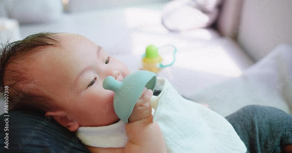 Close-up of a serene Sweet infant child cradled gently in arms, gazing calmly with shiny eyes, against a soft indoor background with a gentle delicate hand holding a toy at home Close-up of a serene Sweet infant child cradled gently in arms, gazing calmly with shiny eyes, against a soft indoor background with a gentle delicate hand holding a toy at home