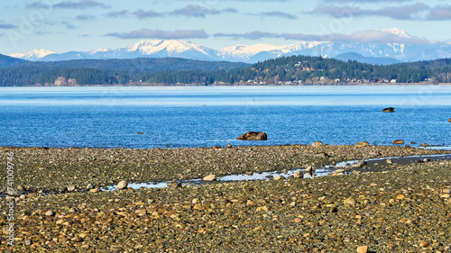 View from a rocky beach acroos the ocean strait to distant islands and snow capped mountains. photo