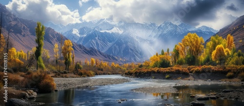 A picturesque river meandering through a lush valley, embraced by towering mountains and verdant trees, under a clear sky with fluffy clouds