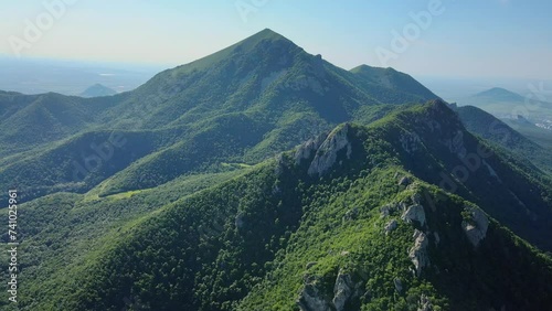 Aerial view of a sunny mountain with treecovered slopes photo