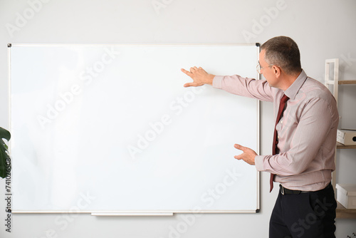 Male teacher pointing at flipboard in classroom photo