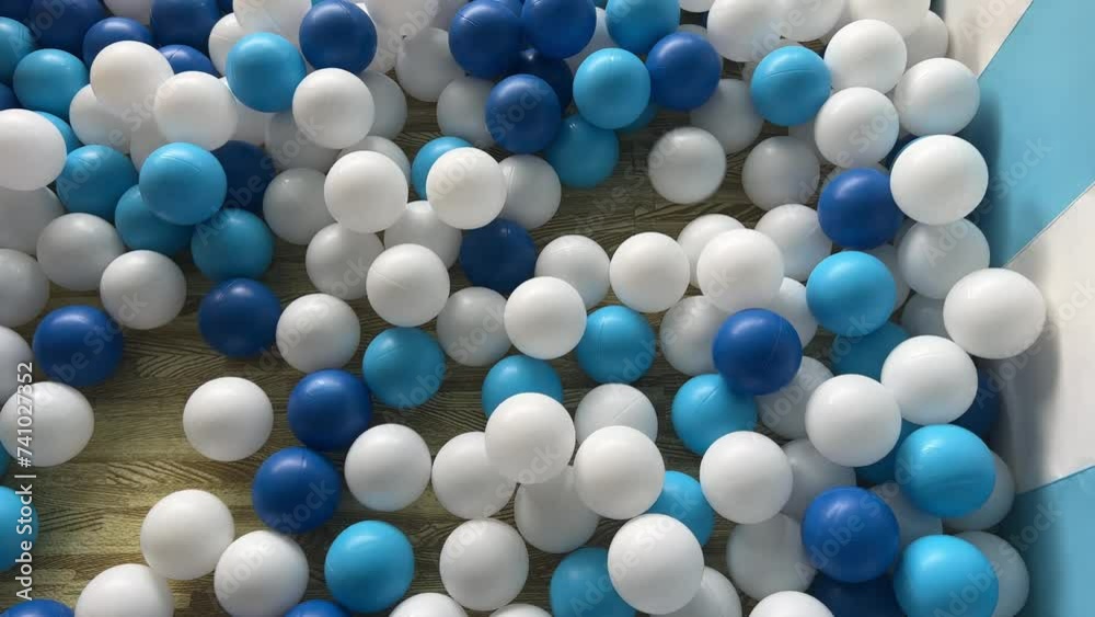 there are a lot of blue and white plastic balls in the dry pool children is coming there are a lot of blue and white plastic balls in the dry pool children is coming