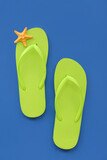 Pair of green flip flops and starfish on blue background