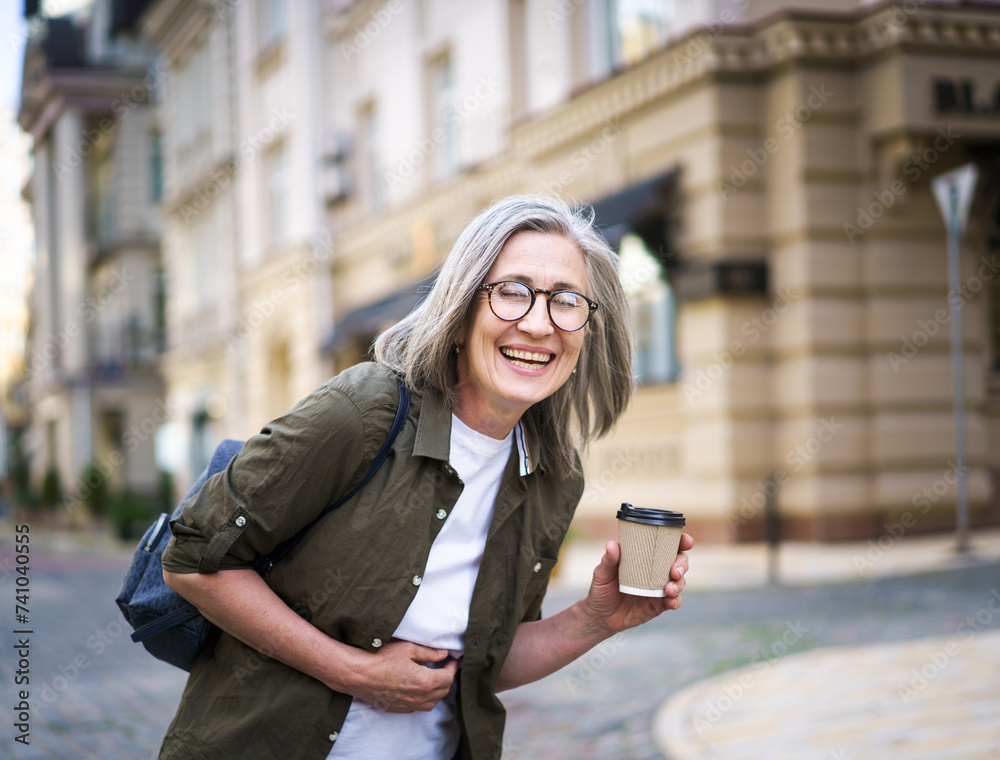 Fototapeta premium A woman wearing glasses holds a cup of coffee in her hand.