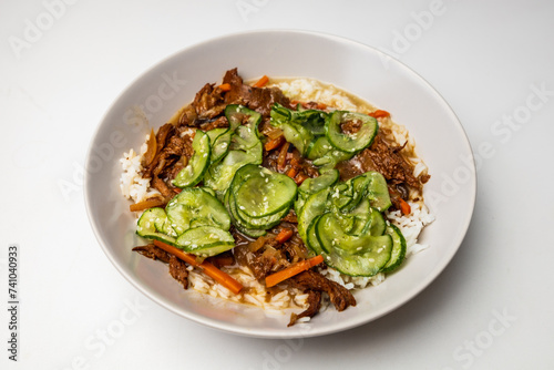 Colorful asian dish with white rice carrots mushrooms and cucumber slices with some white sesame