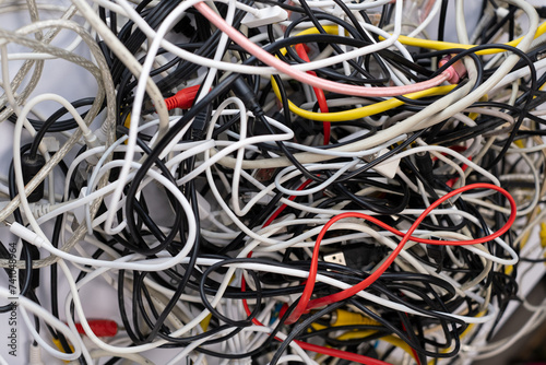 A pile of various used tech peripheral cables, connectors, and plugs, including universal standards for computers, audio and video cables, e-waste concept.
