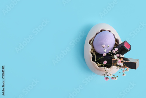 Basket in shape of Easter egg with lipsticks and flowers on blue background