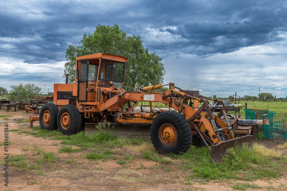 Orange grader parked on the side of a road, Namibia Orange grader parked on the side of a road, Namibia