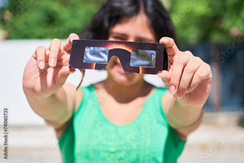 Happy young latina woman with solar eclipse glasses, watching a solar eclipse photo