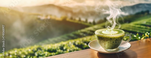 Aromatic matcha tea with a delicate foam art, overlooking tea fields. This warm cup is set before a vista of vibrant green rows of tea. Panorama with copy space. photo